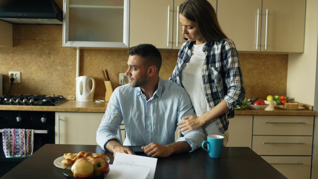 A couple reviews life insurance paperwork and household finances at a kitchen table.